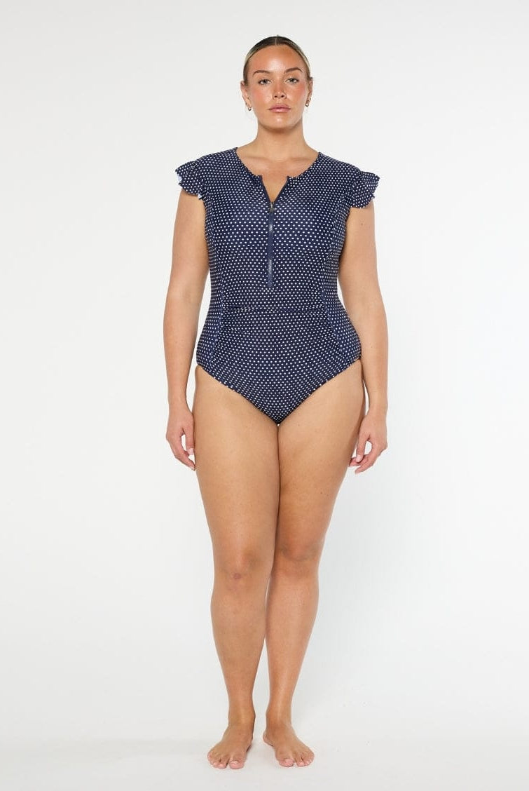 Woman wearing a navy polka dot swimsuit on a white background