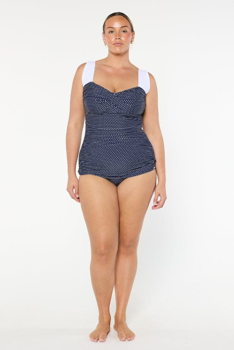 Woman wearing a navy patterned swimsuit on a white background