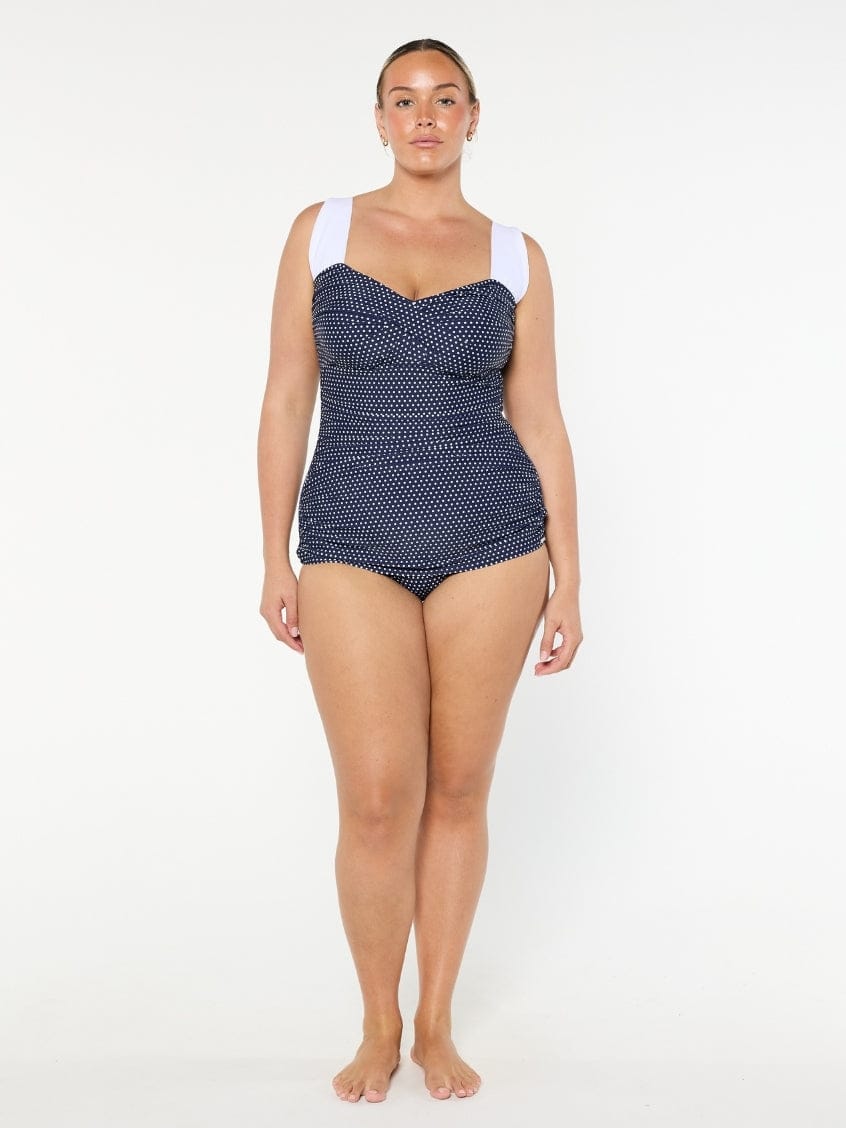 Woman wearing a navy patterned swimsuit on a white background