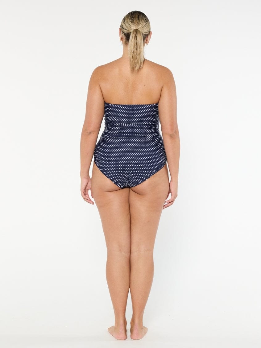 Woman wearing a strapless polka dot swimsuit on a white background