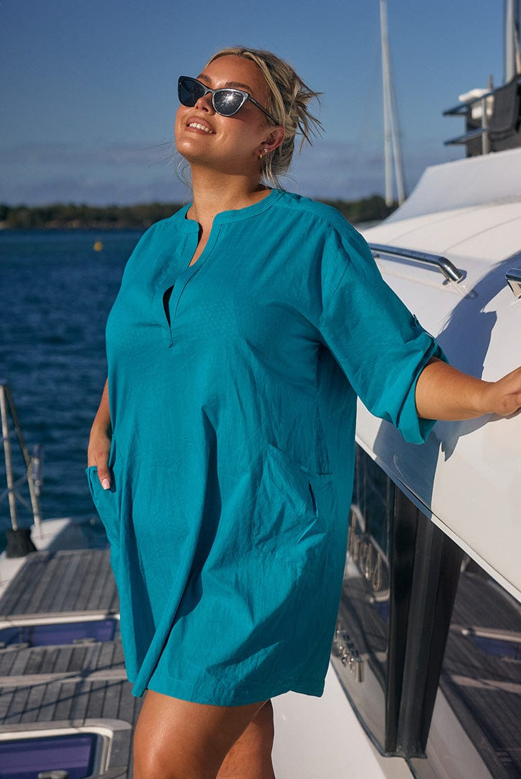 Blonde model wearing ocean coloured beach dress on boat