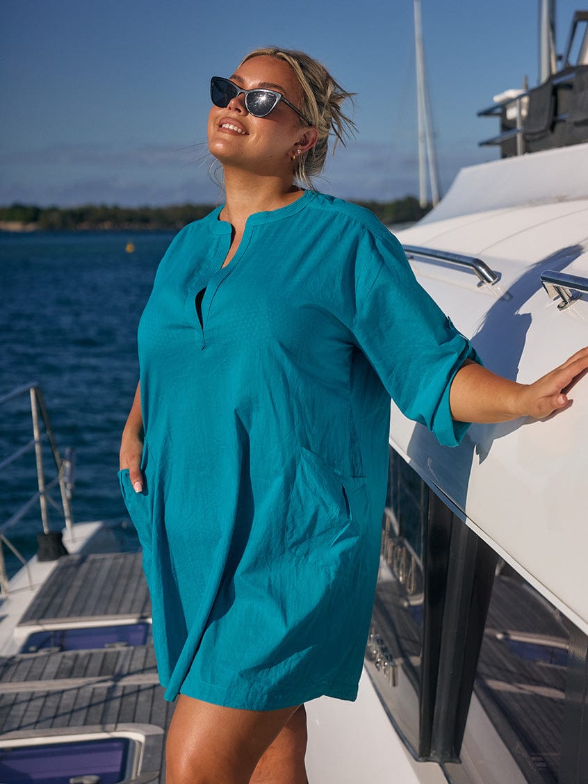 Blonde model wearing ocean coloured beach dress on boat