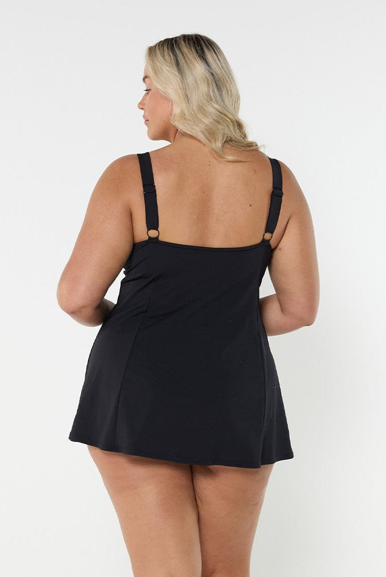 Back of woman in studio wearing short length swim dress in paisley print with adjustable straps