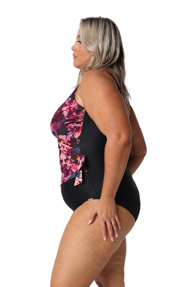 Side of plus size model wearing crossover one piece swimsuit in pink and black floral