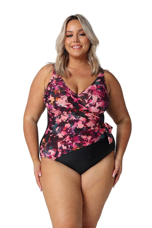 Blonde model in studio wears crossover v neck floral one piece for curve women
