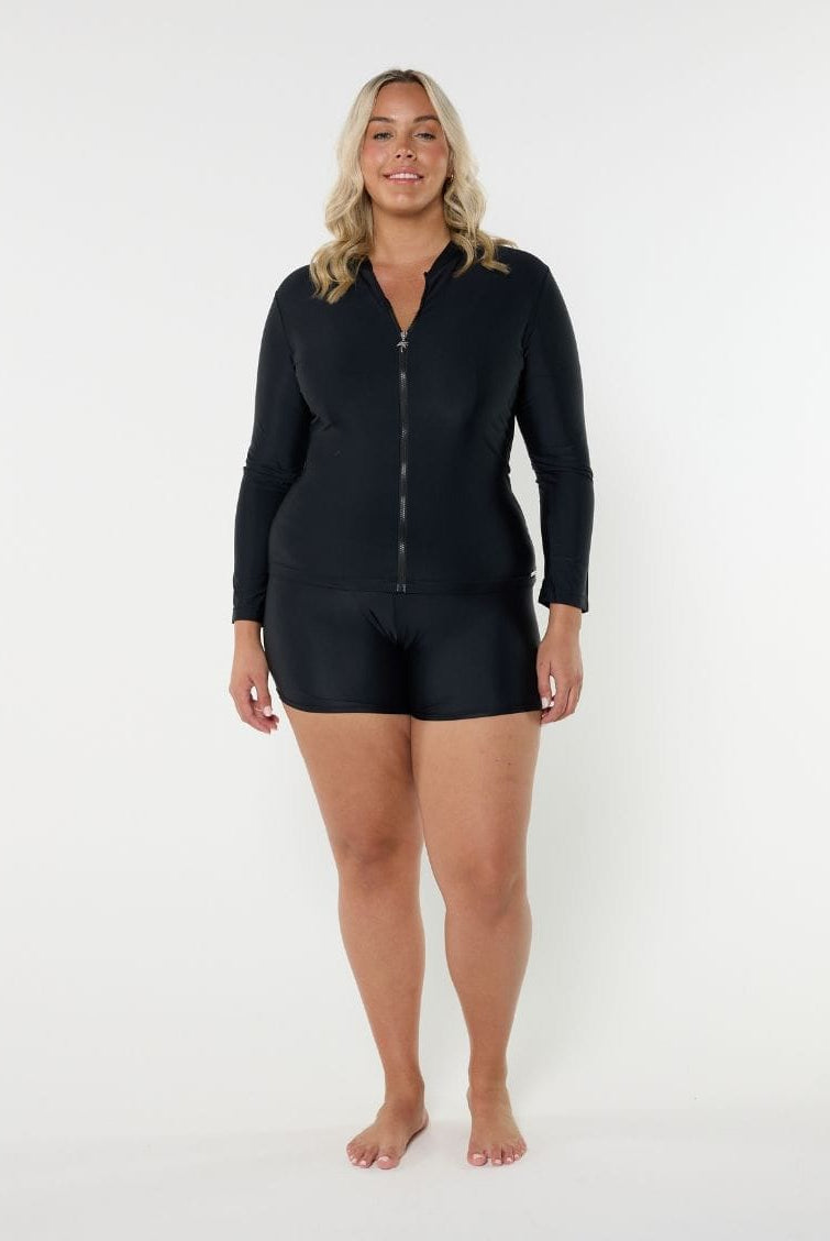 Woman wearing a rash black zip-up swimsuit top on a white background