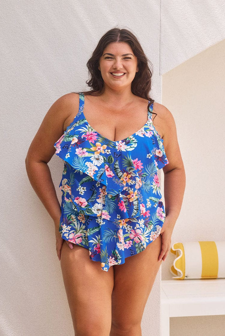 Brunette model wears tummy control tankini top with shelf bra in blue floral print