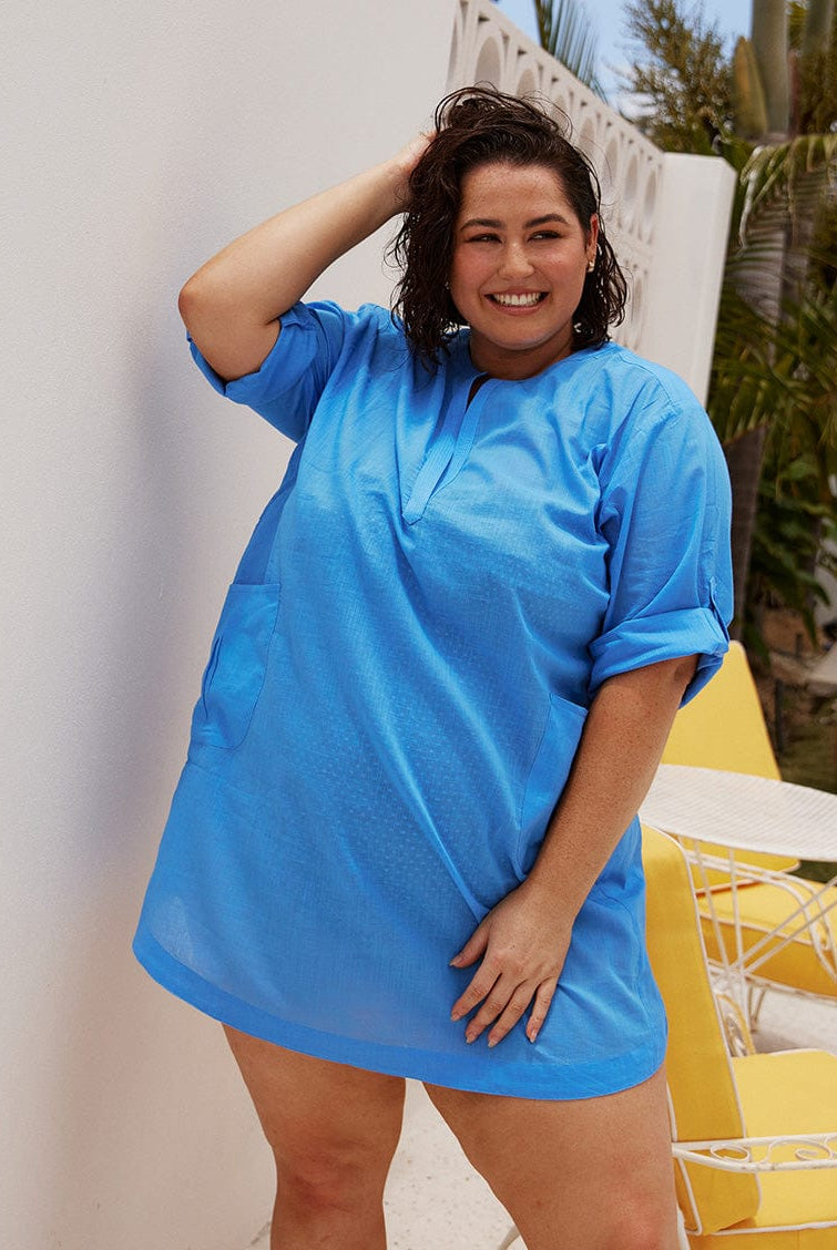 Brunette plus size model wears flattering kaftan over shirt in blue