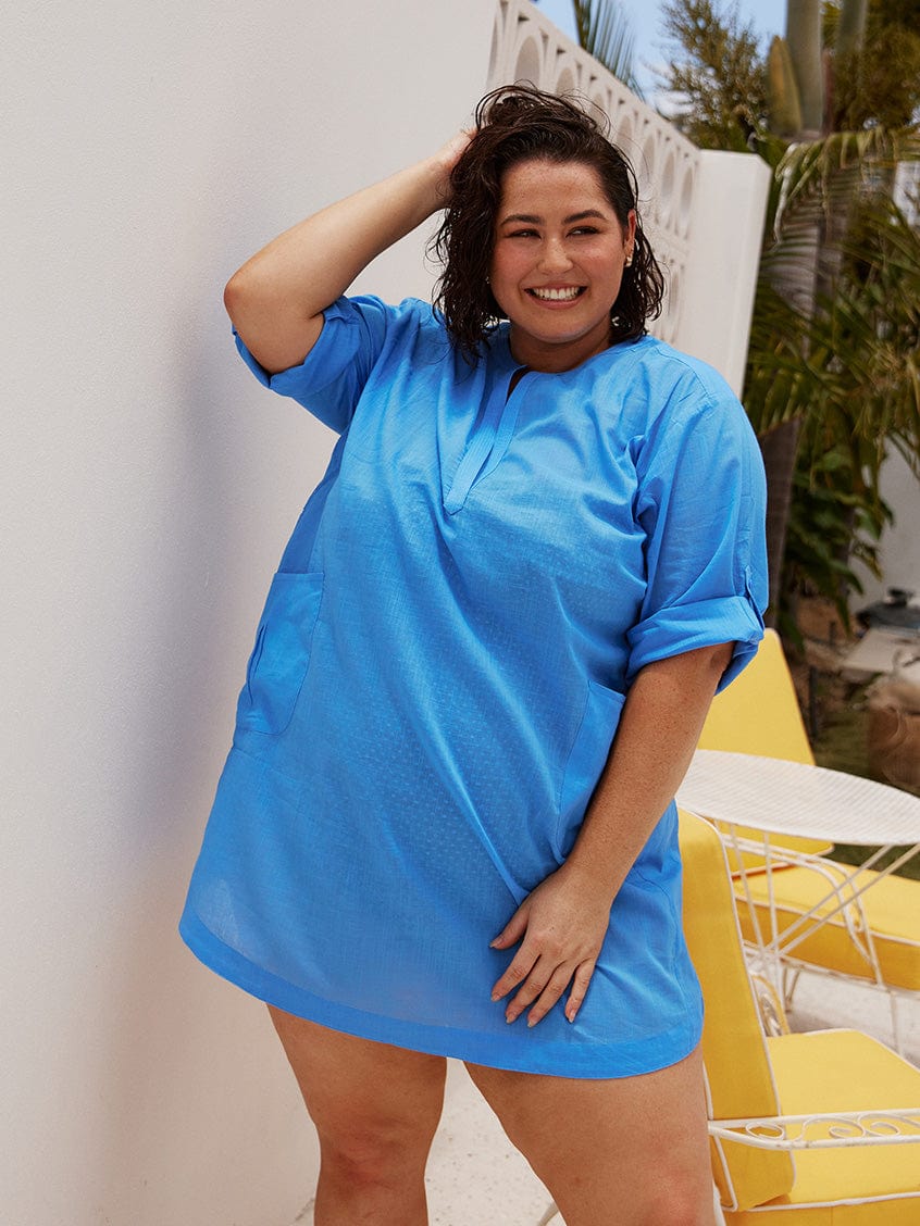 Brunette plus size model wears flattering kaftan over shirt in blue