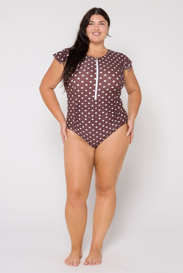 Woman wearing a brown polka dot swimsuit on a white background