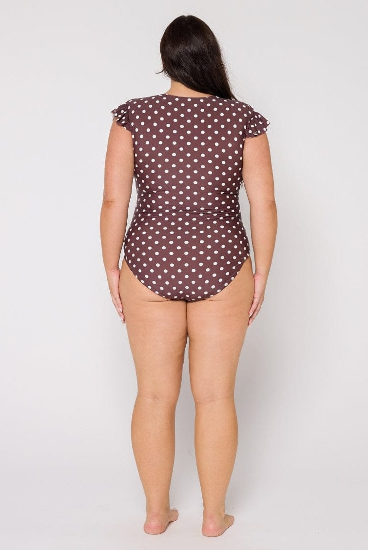 Woman wearing a polka dot swimsuit on a plain background