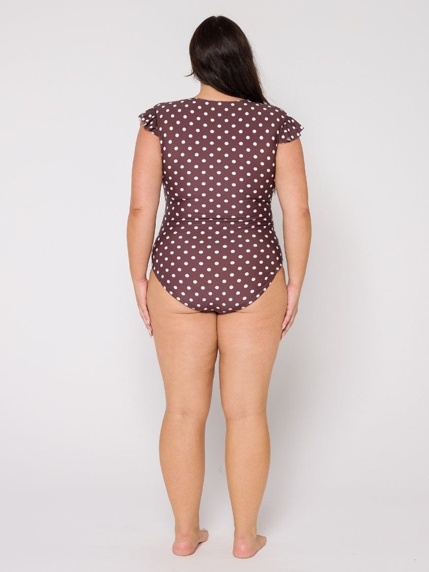 Woman wearing a polka dot swimsuit on a plain background