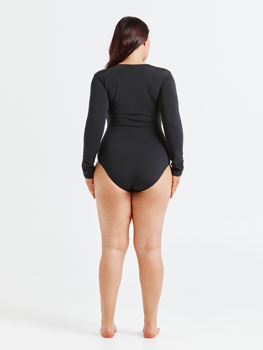 Person wearing a black long-sleeve swimsuit on a white background