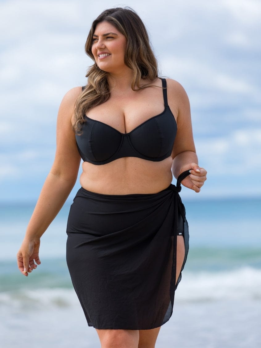 Woman wearing a black bikini and sarong on a beach