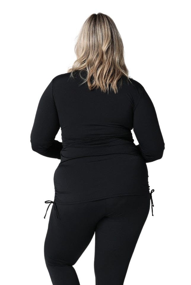 Back of model wearing plus size swim shirt with long sleeves with ruching detail on side in chlorine resistant