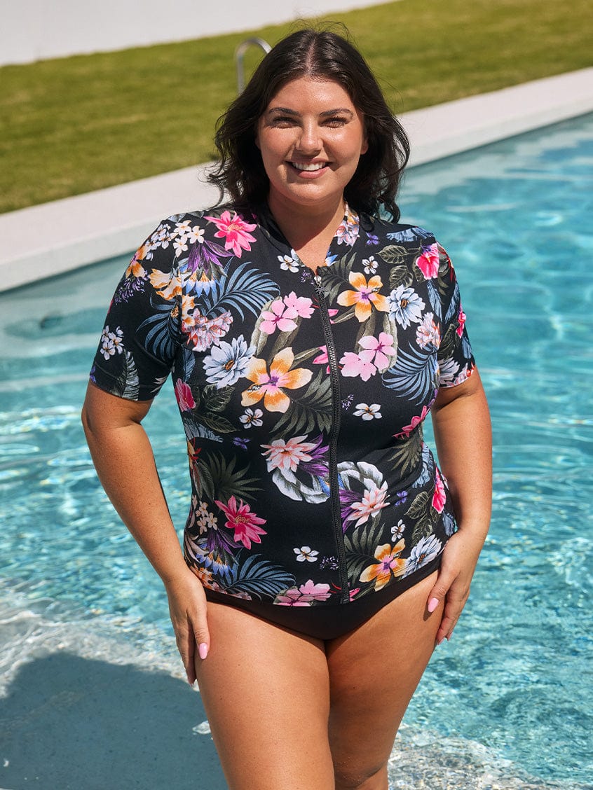 Brunette model wears short sleeve chlorine resistant rash vest with full front zip