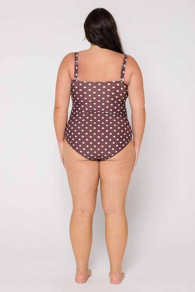 Woman wearing a polka dot swimsuit on a plain background