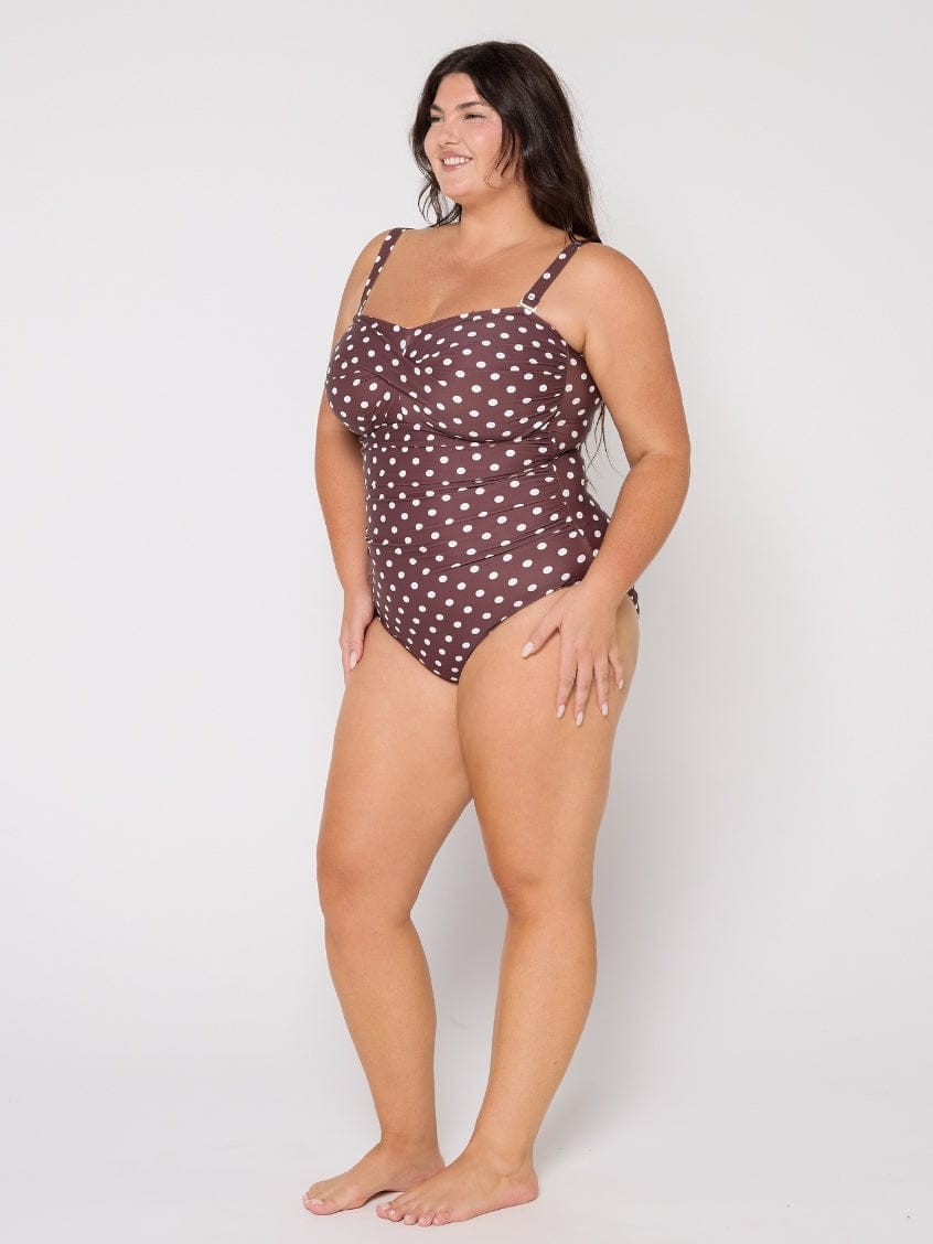 Woman wearing a brown polka dot swimsuit on a white background
