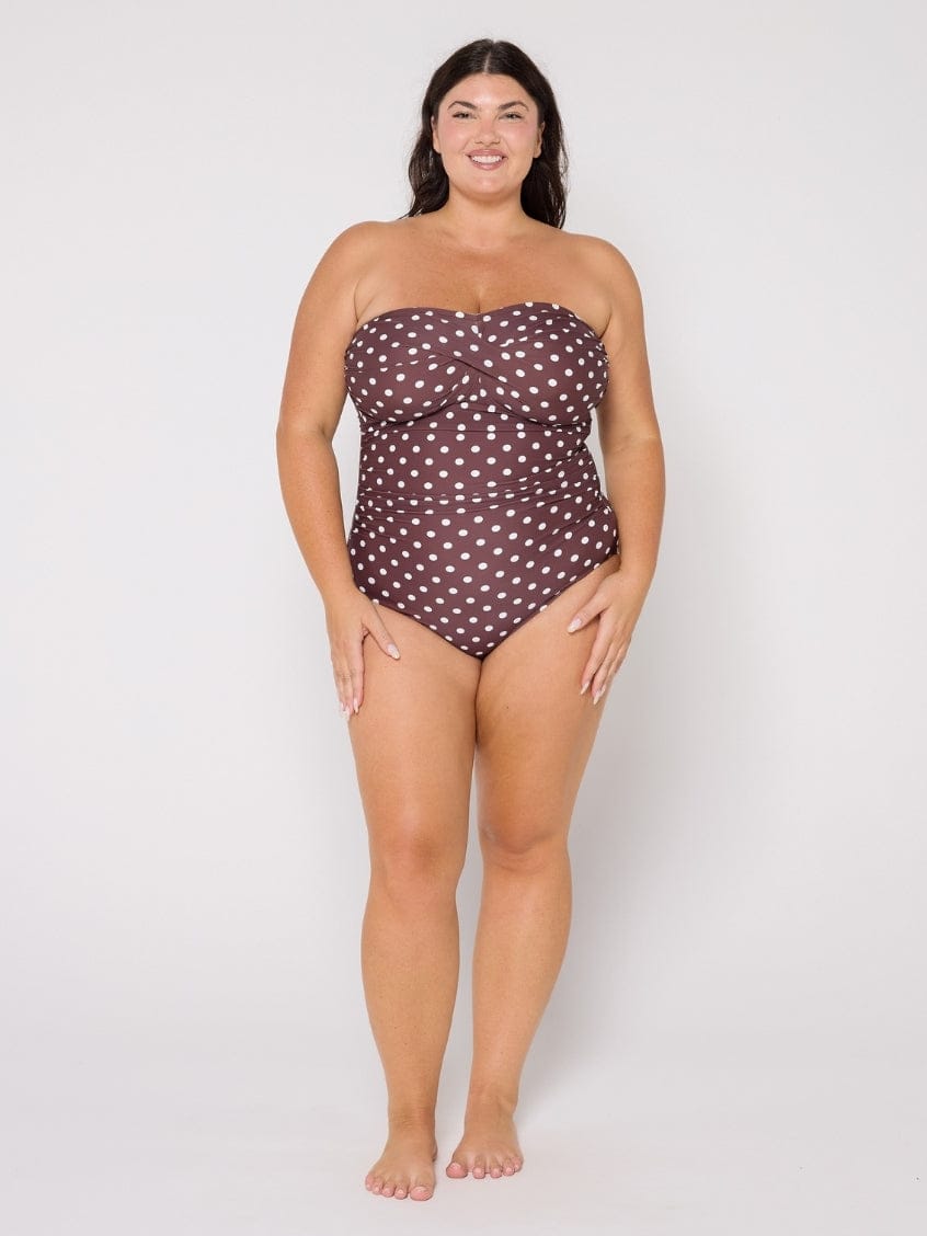 Woman wearing a strapless polka dot swimsuit on a white background