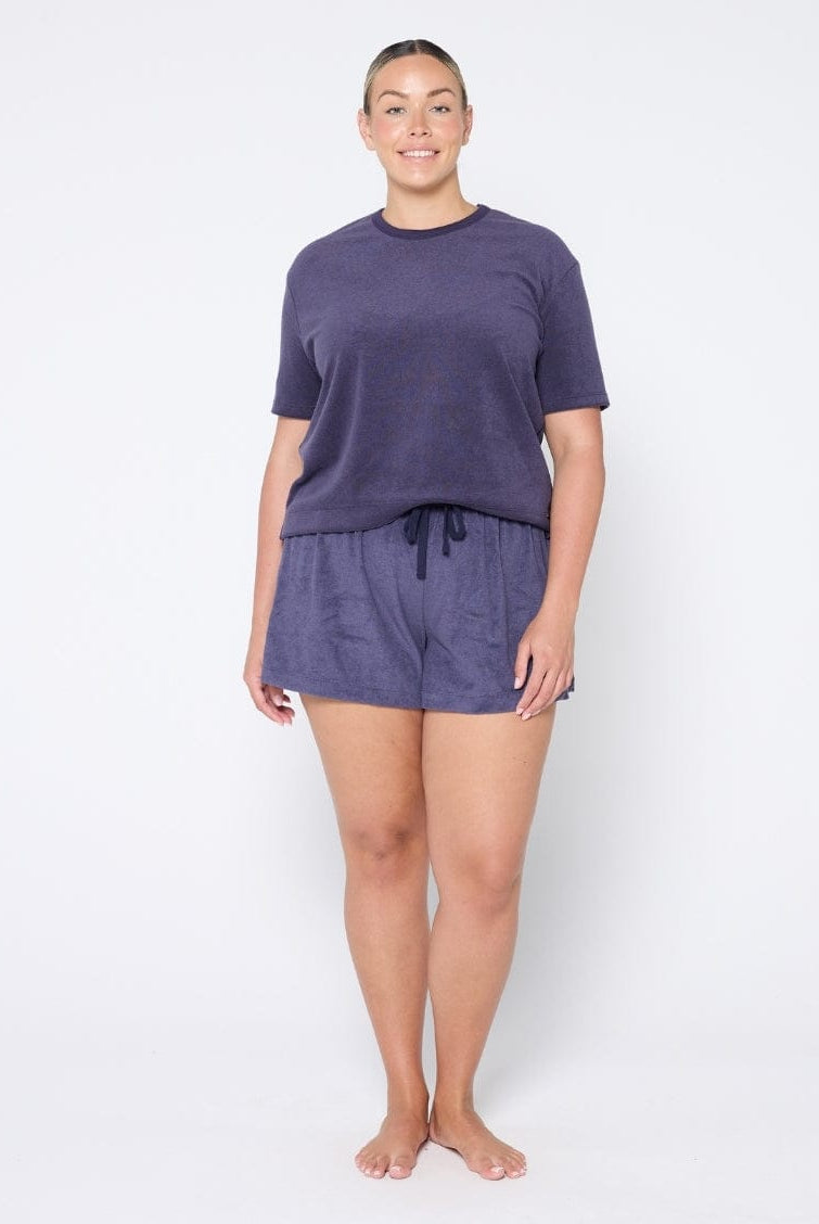 Woman wearing a navy terry towelling set on a white background