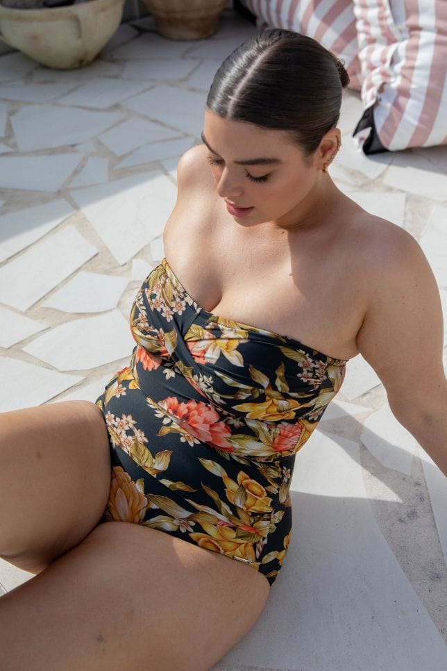 model sitting wearing a black floral plus size one piece women's swimsuit