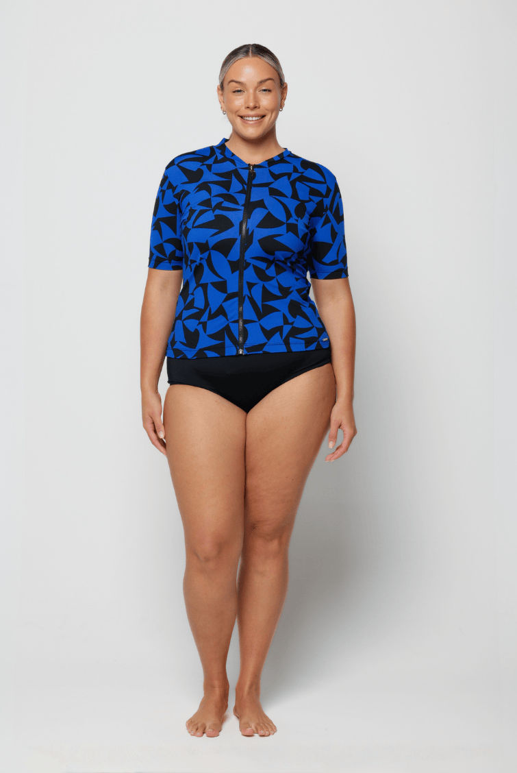 Person wearing a blue patterned rash guard and black shorts on a white background