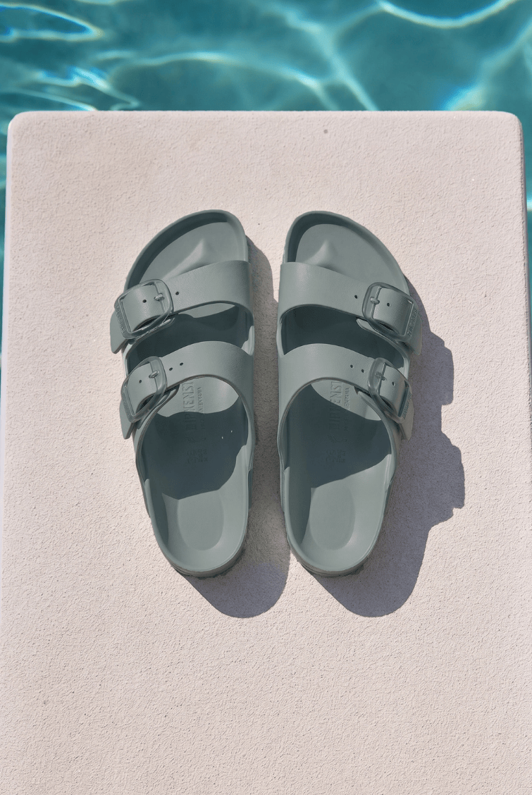 Sage birkenstock sitting on diving board by pool with two straps