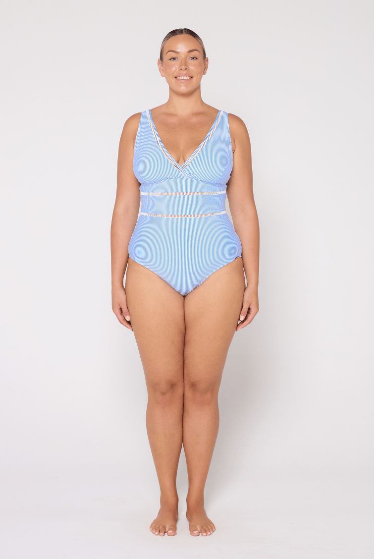 Woman wearing a blue v neck one piece swimsuit on a white background