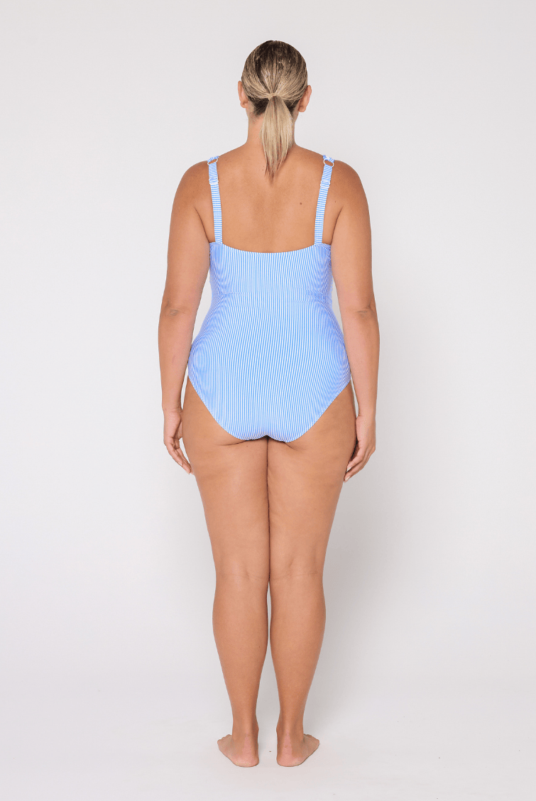 Woman wearing a light blue V neck swimsuit with adjustable straps on a white background