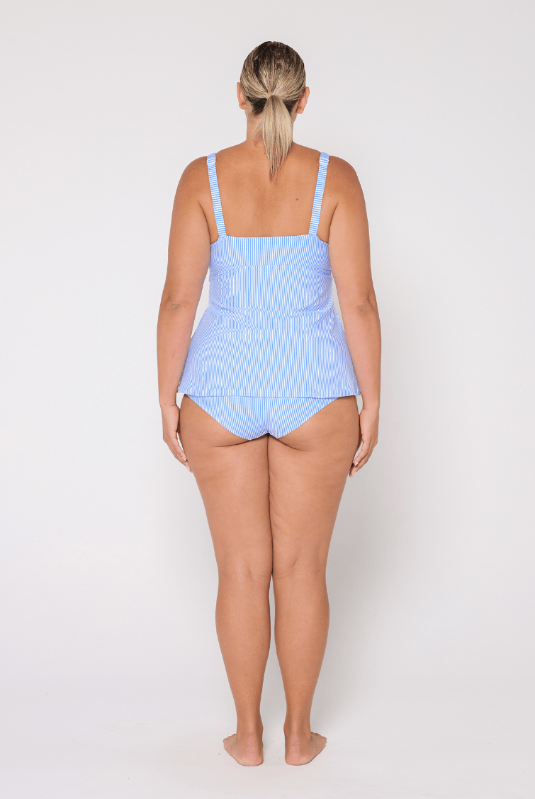 Woman wearing a light blue tankini swim top on a white background
