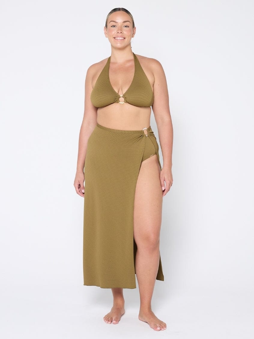 Woman wearing a green bikini set with a long skirt on a white background