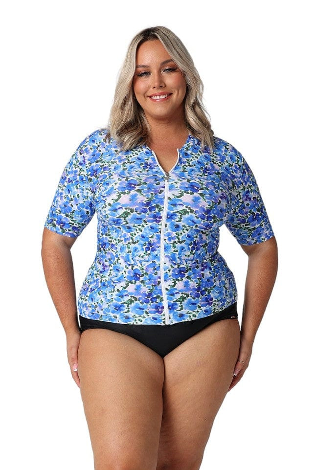 Front of model in studio wearing zip front rash vest in water colour floral print