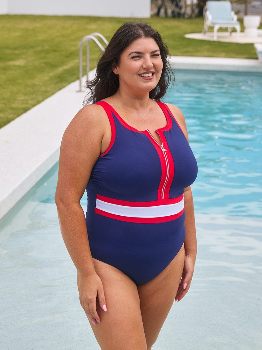 Woman wearing a navy blue and red swimsuit by a pool