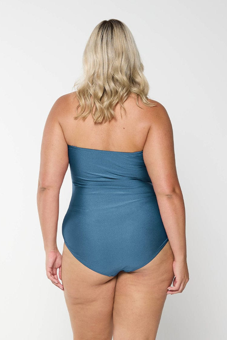 Back of blonde curve model in studio wearing a grey bandeau one piece with removable and adjustable straps