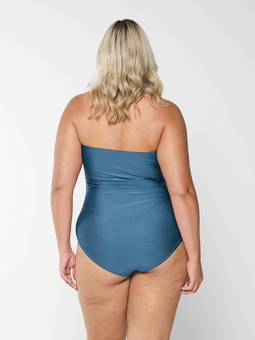 Back of blonde curve model in studio wearing a grey bandeau one piece with removable and adjustable straps