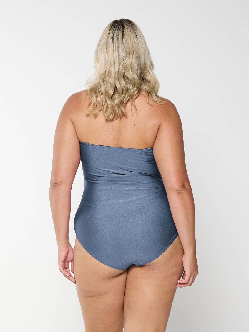 Back of blonde curve model in studio wearing a grey bandeau one piece with removable and adjustable straps