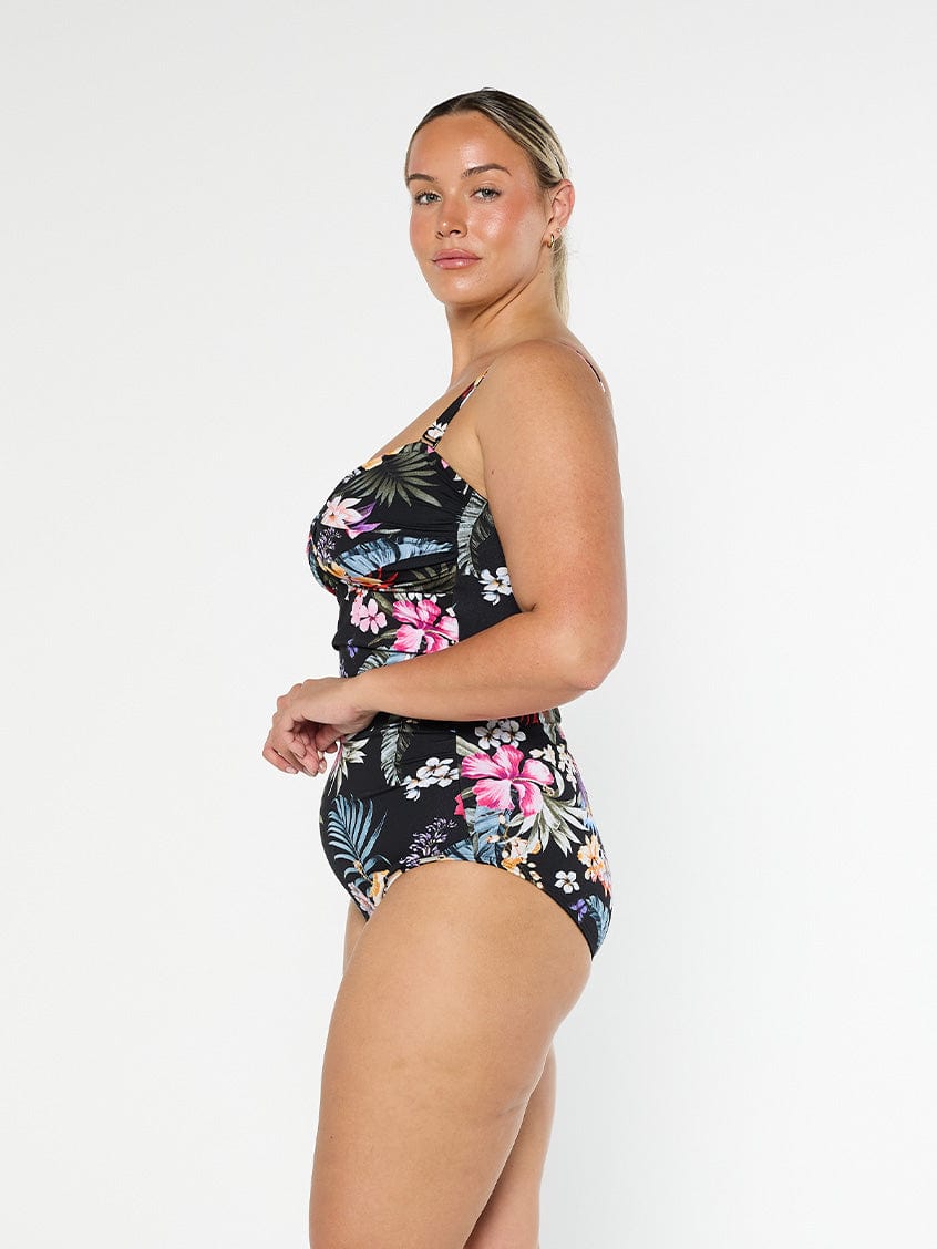Blonde model shows the side of chlorine resistant black floral one piece with removable straps