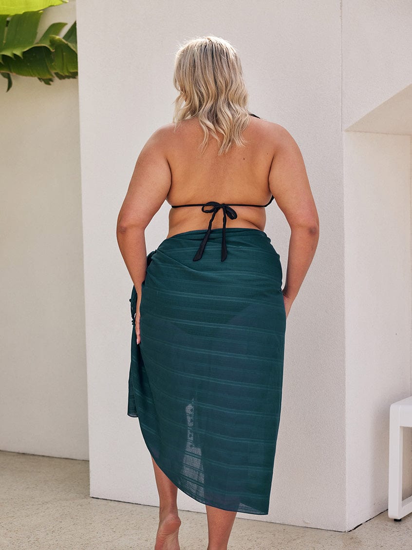 Back of blonde curve model wearing a long cotton sarong in teal colour