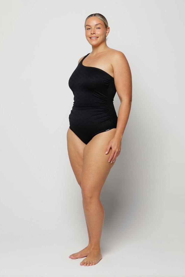 Woman wearing a black one-shoulder swimsuit on a white background
