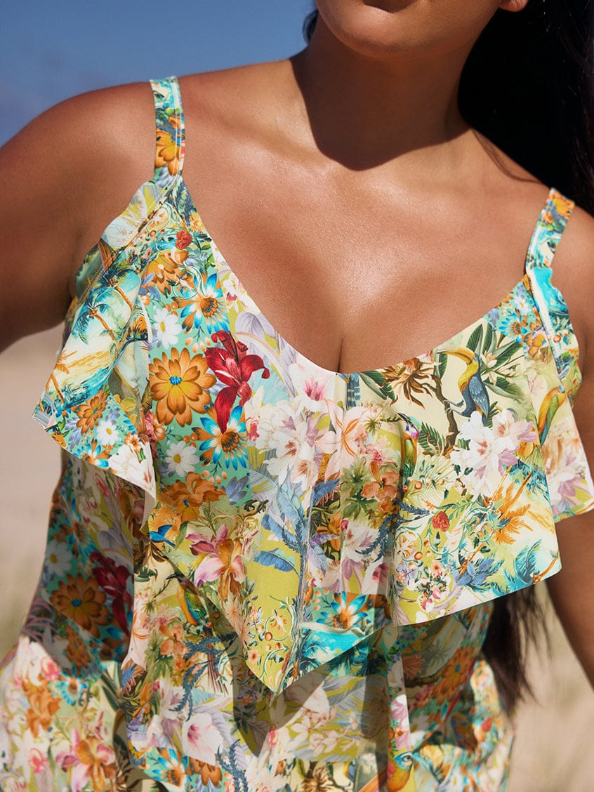 Woman wearing a colorful floral dress against a clear blue sky.