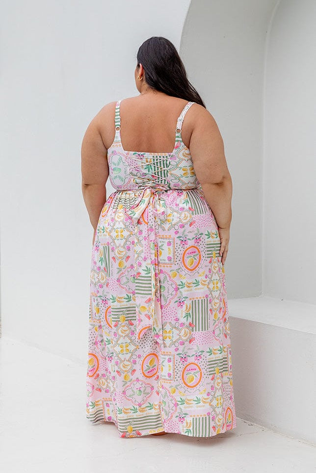 Back of model wearing high waisted maxi skirt with tie detail in fruit pattern for curve women