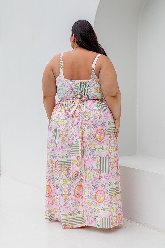 Back of model wearing high waisted maxi skirt with tie detail in fruit pattern for curve women