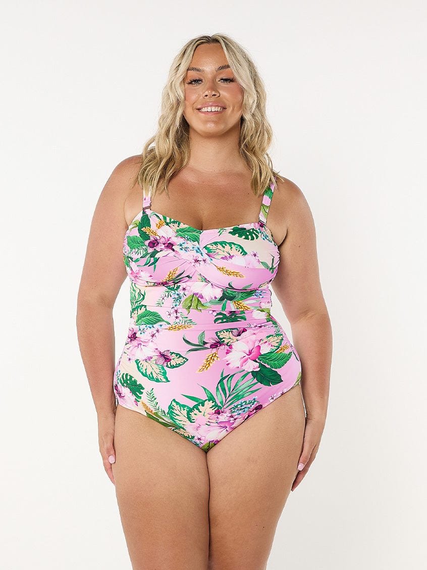 Blonde model in studio wearing a tropial print bandeau one piece with removable and adjustable straps