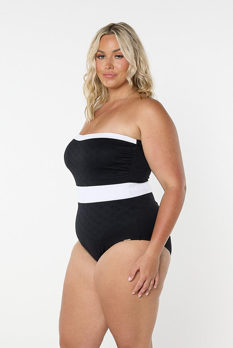 Woman wearing a black and white strapless swimsuit on a white background