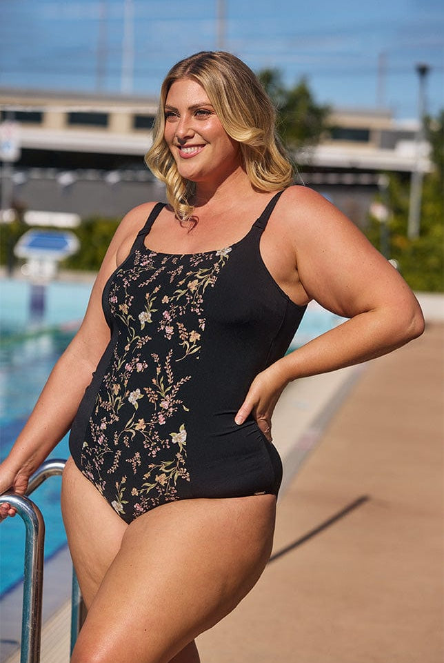 Model showing side of black floral one piece swimsuit