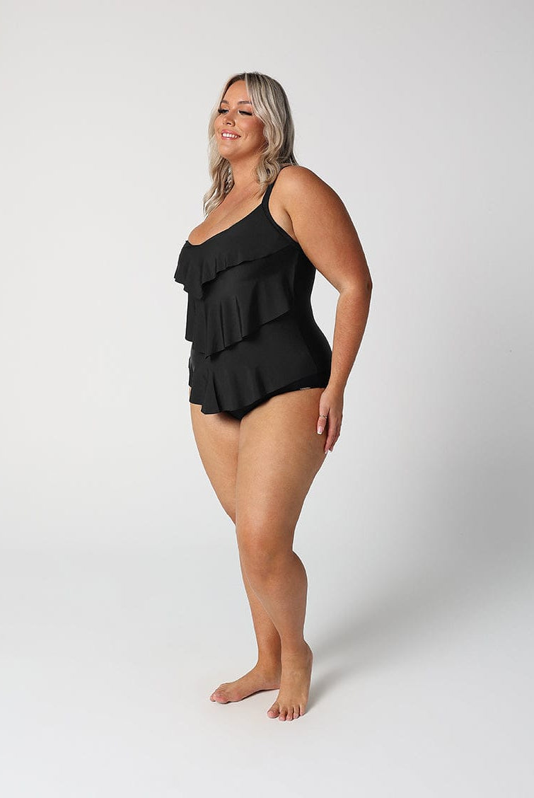Woman wearing a black ruffled swimsuit on a white background