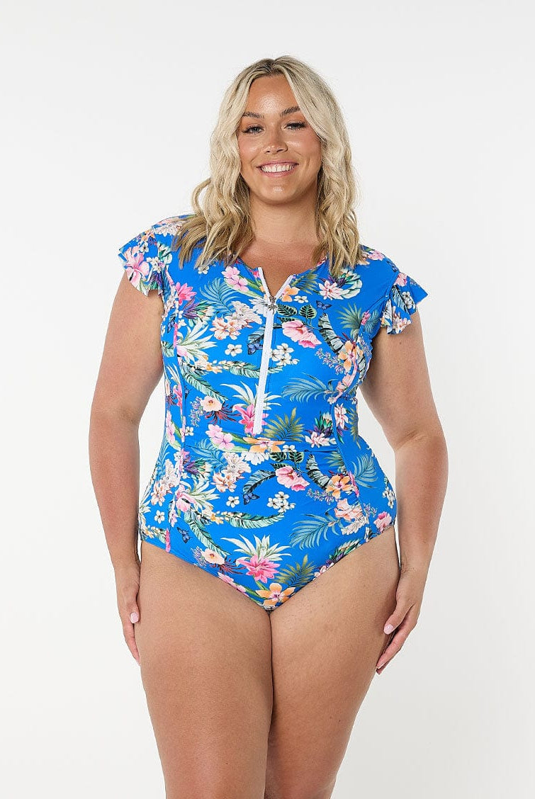 Blonde model shows the front of zip up frill sleeve one piece in blue floral fabric