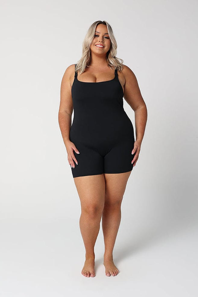 women standing in front of a white wall wearing a black boyleg one piece