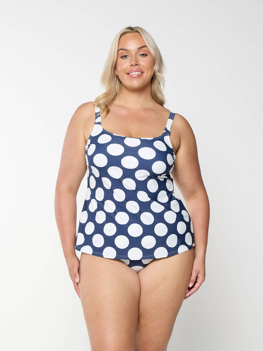 Blonde model shows tummy control swim bottom in navy and white polkadot pattern