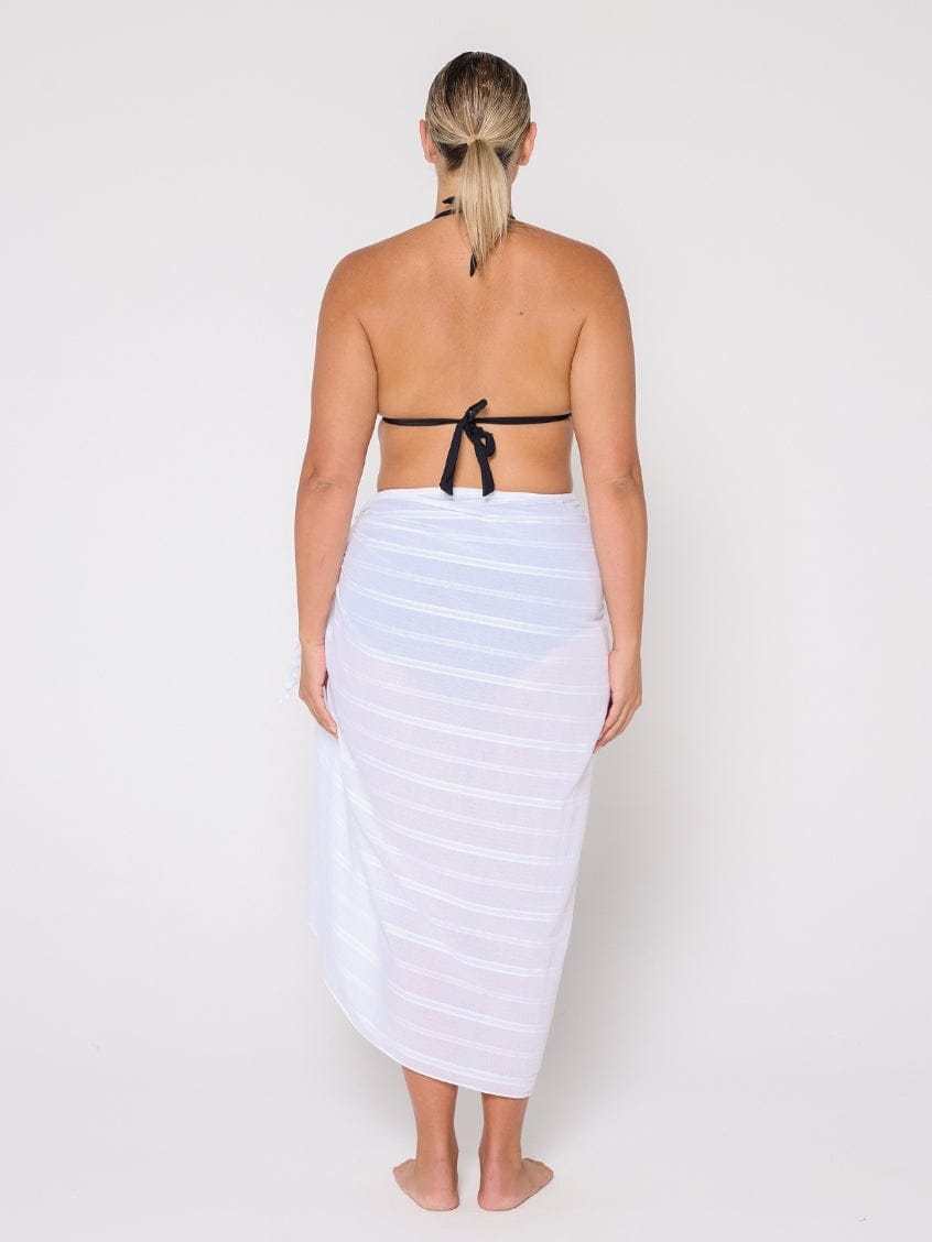 Woman wearing a black strapless top and white striped towel on a plain background